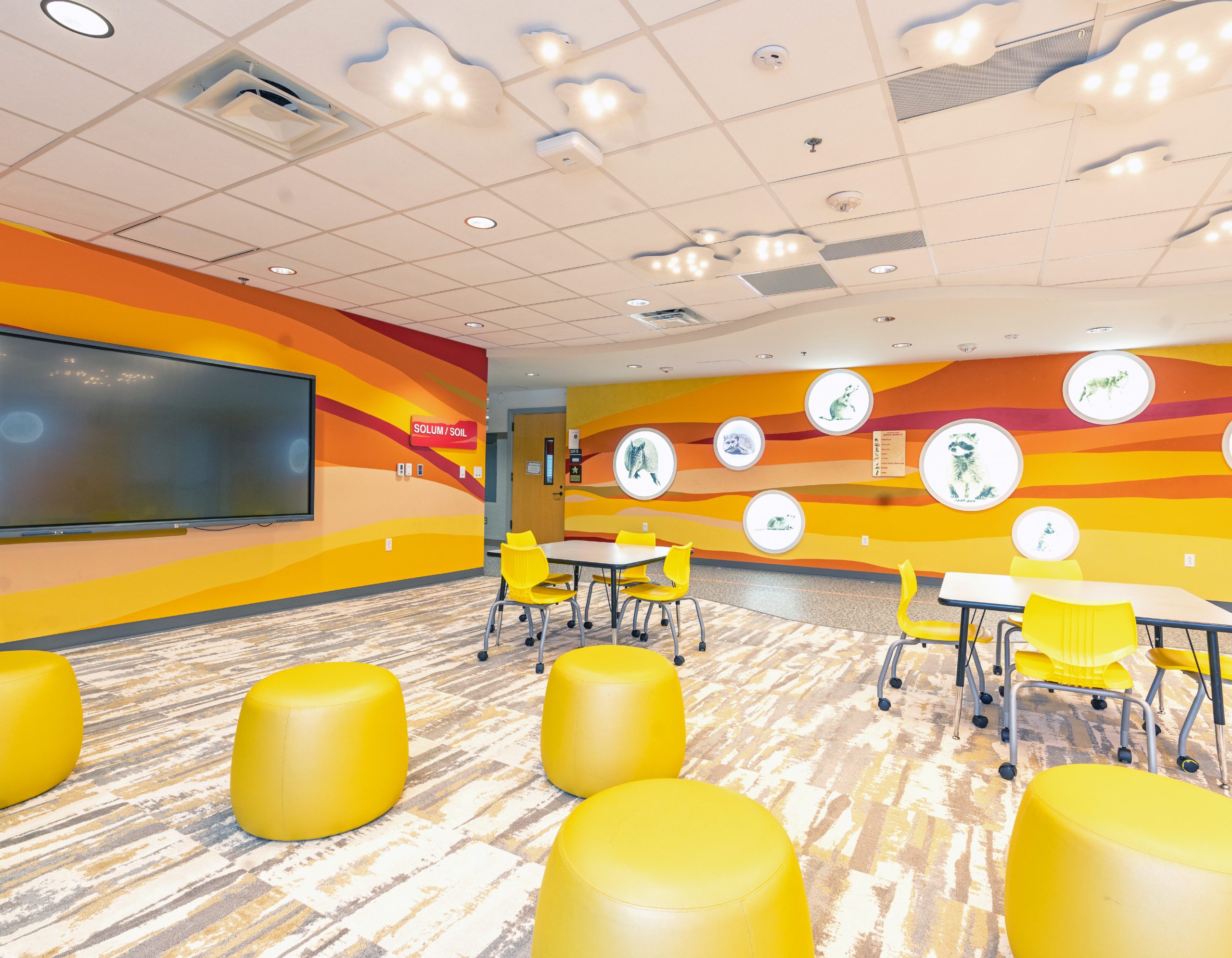 Green hallway connecting themed learning zones with Terra/Land room signage and dimensional ceiling features at Armstrong Elementary