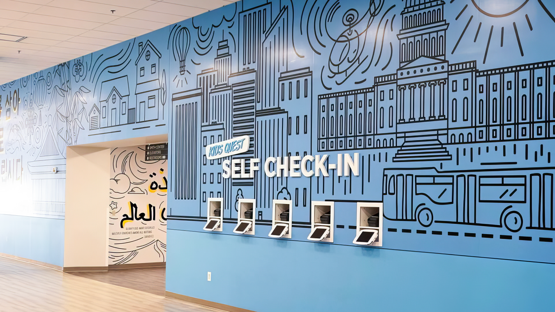 interior signage for kids self check-in kiosk that also has interior wall design of different buildings, cars, helicopter and more