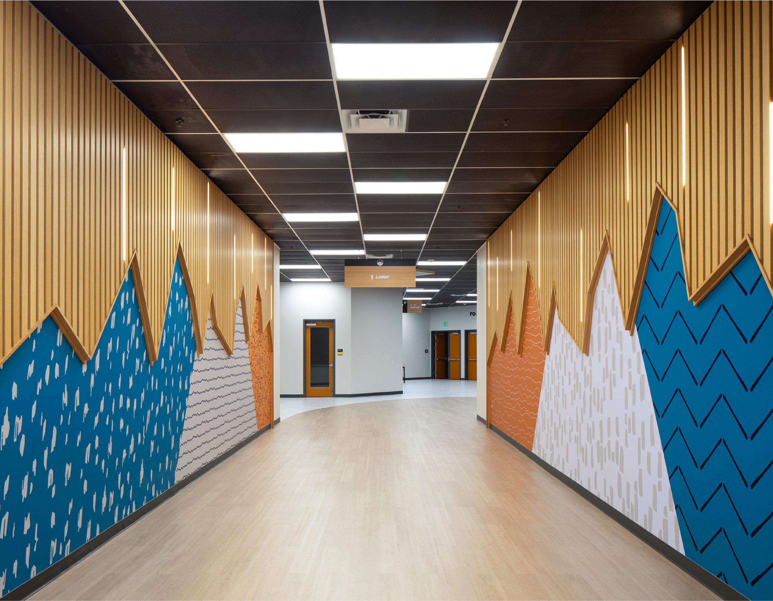 Interior signage and supergraphic mountain mural wall design in a Flatirons church children's ministry hallway by Enviropop
