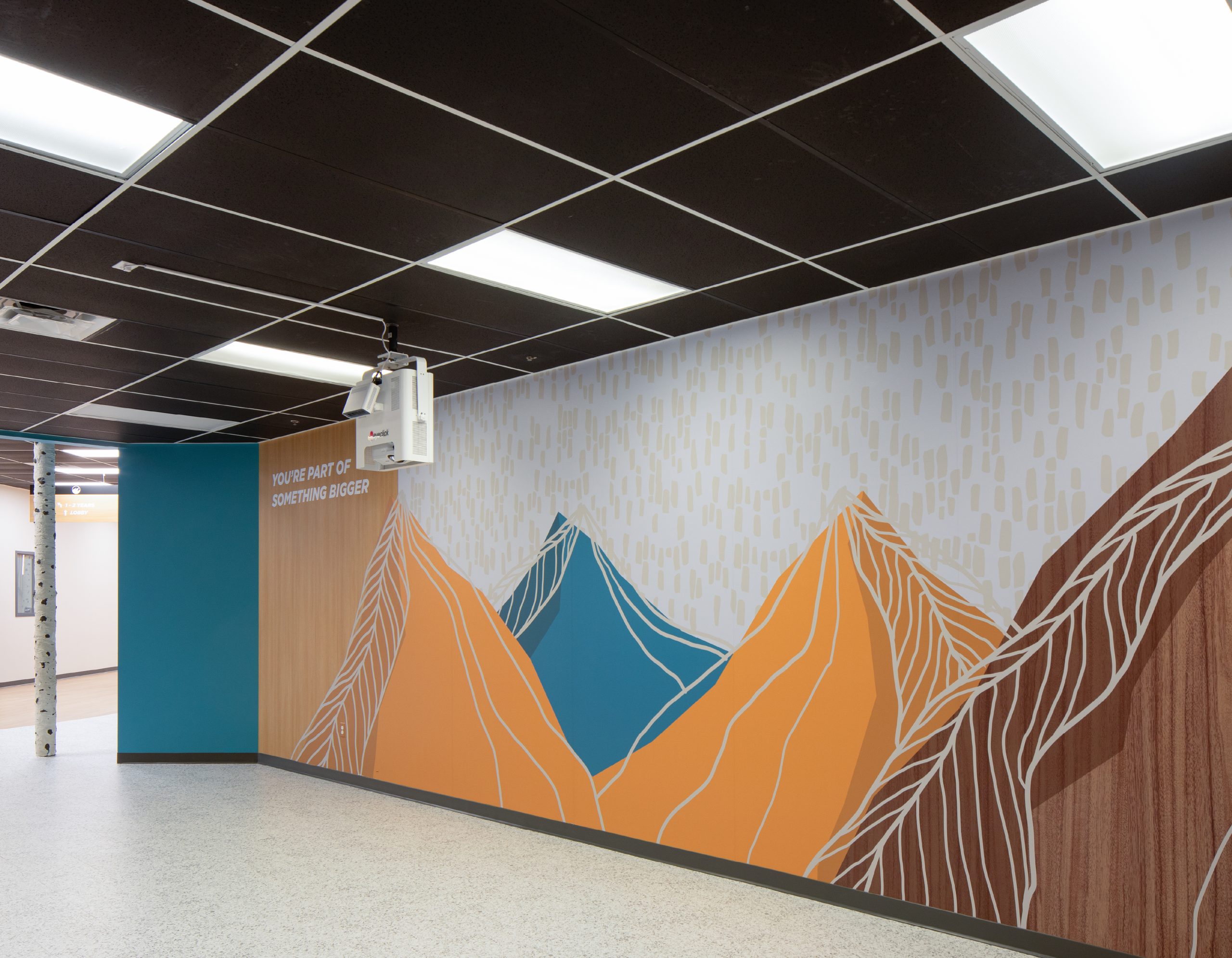 Environmental graphic design mountain mural with wayfinding messaging in a Flatirons church hallway, part of Enviropop's interior branding work