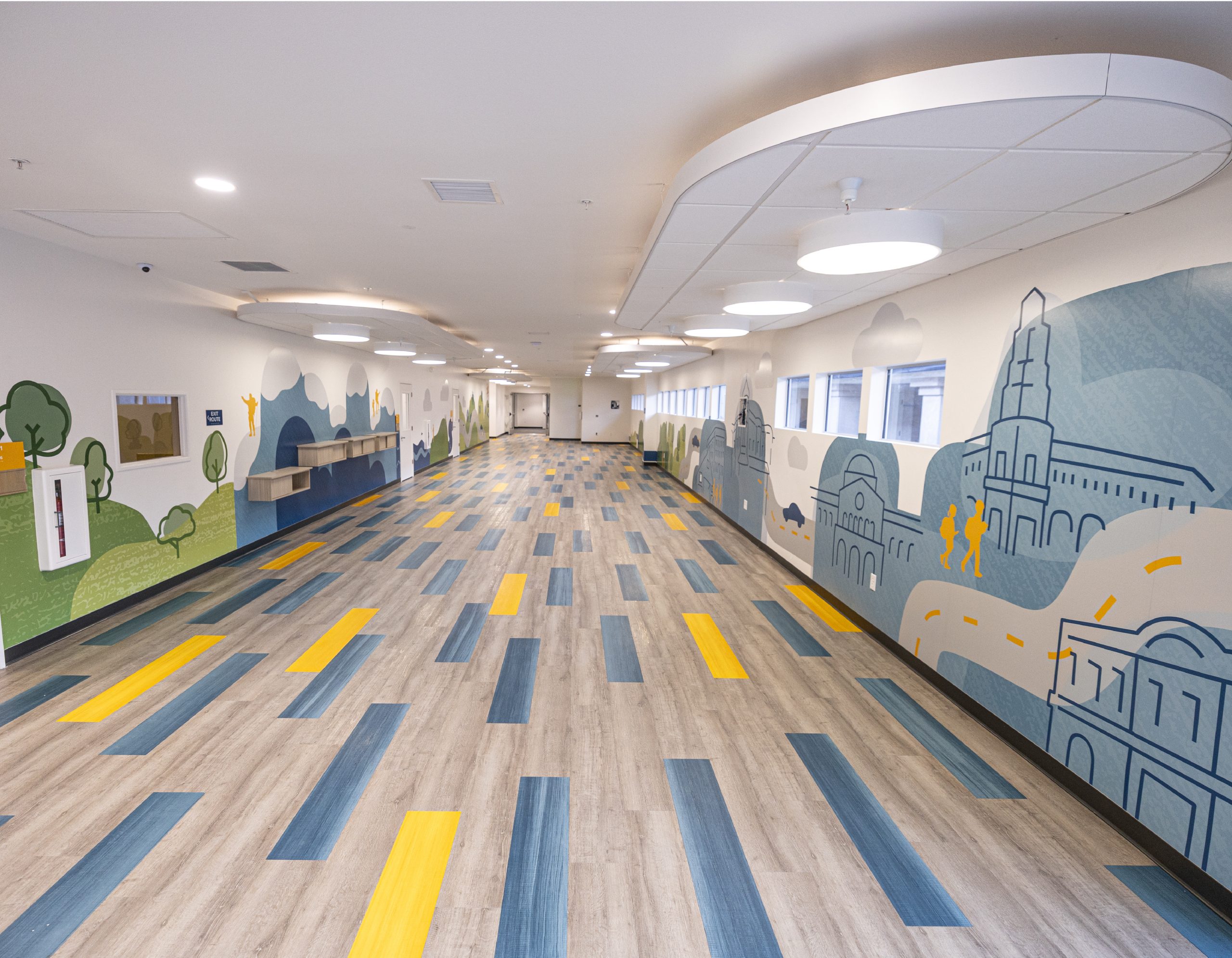 Full-campus interior mural system with city and nature supergraphics lining the hallway at EFCC Chico, designed by Enviropop