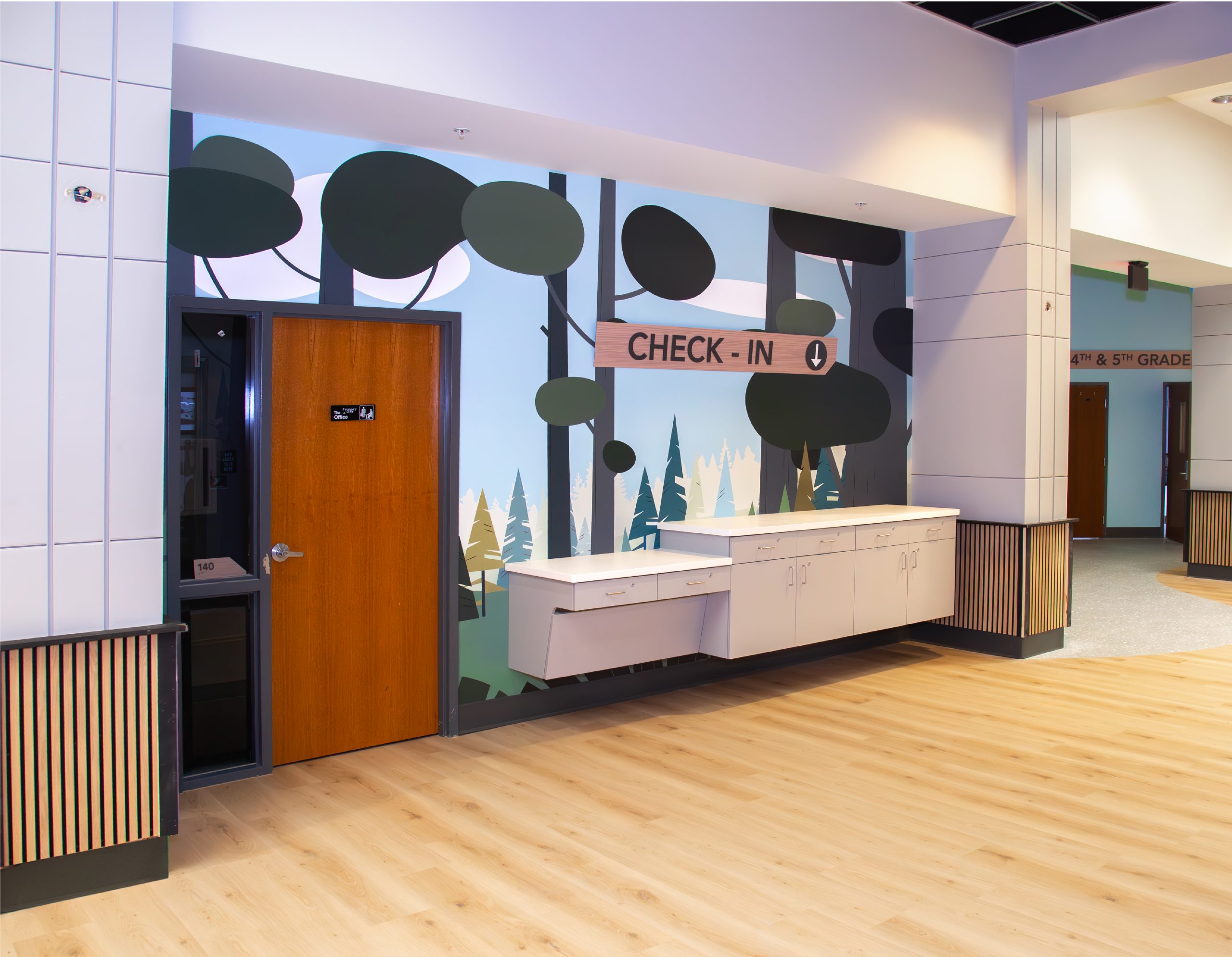 Northwoods Kids check-in area with environmental graphic design forest mural and wayfinding signage by Enviropop